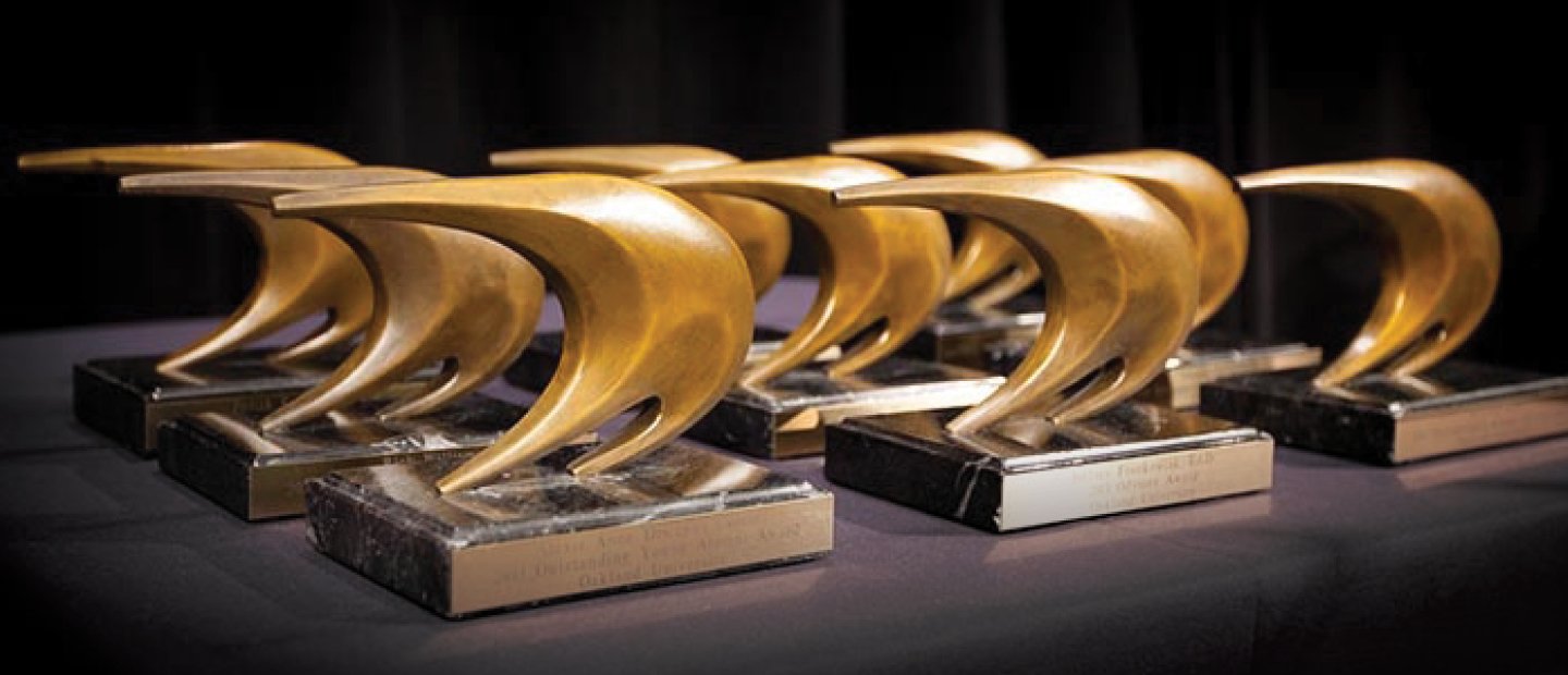gold sail shaped awards lined up on a table