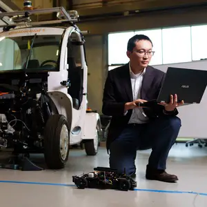 Jun Chen, Ph.D. in a lab with a vehicle.