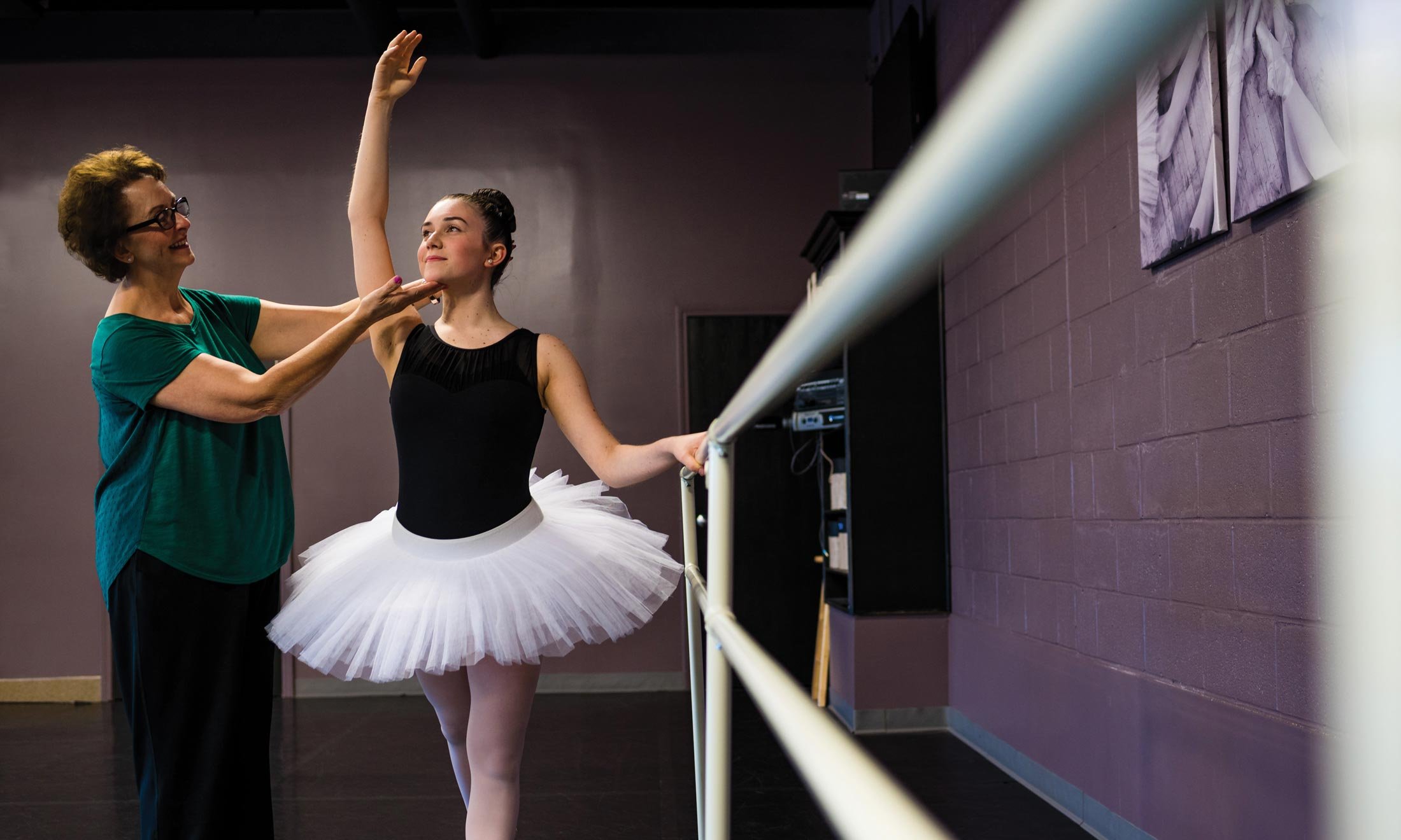 Oakland University alumna Mary Sherman corrects a ballet student's form in the Macomb Ballet Company studio.