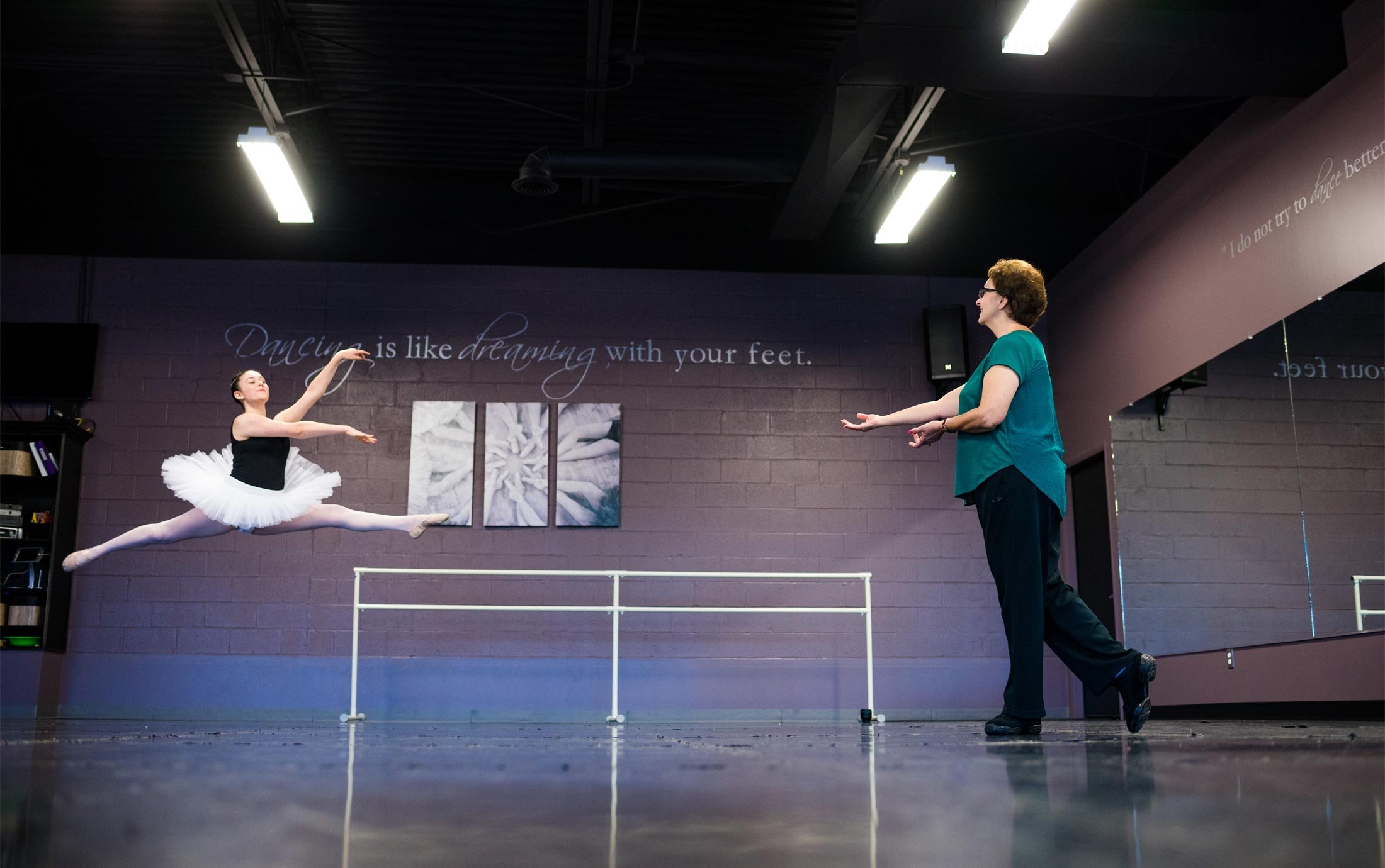 A ballet student practices a jump in the Macomb Ballet Company studio with Oakland University alumna Mary Sherman