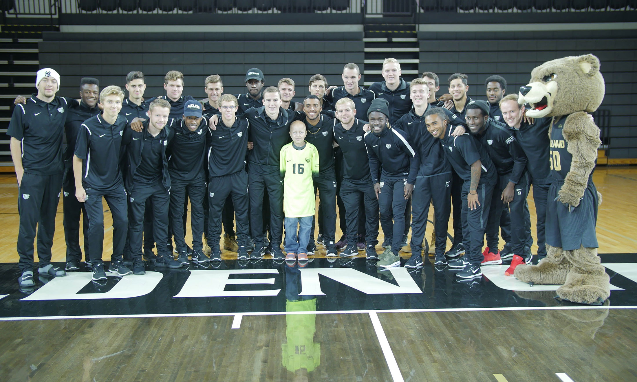 10-year-old Alex VanHolder poses with the Oakland University men's soccer team in the O rena 
