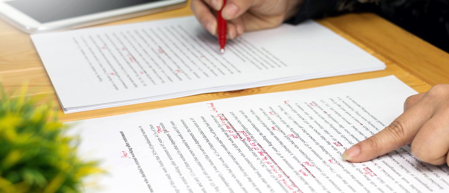 A person proof-reading a document and marking corrections in red pen.