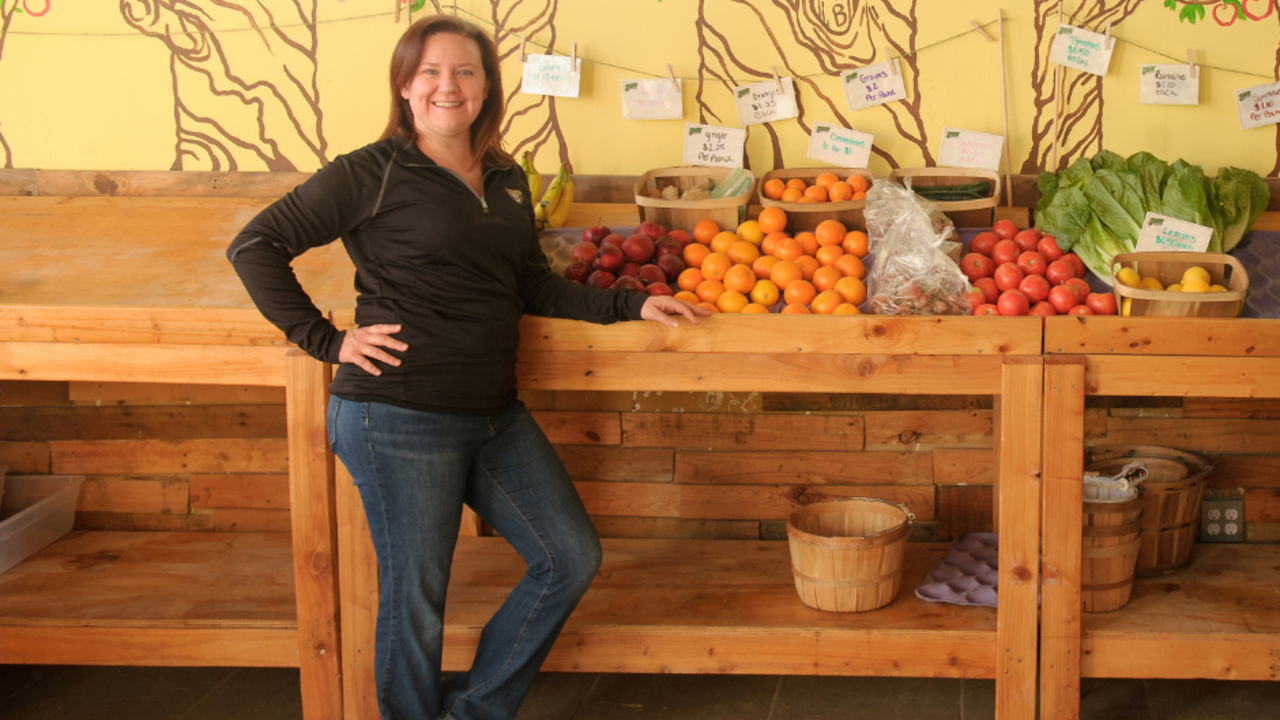 Dr. Jennifer Lucarelli posing for a photo in front of a fruit stand.