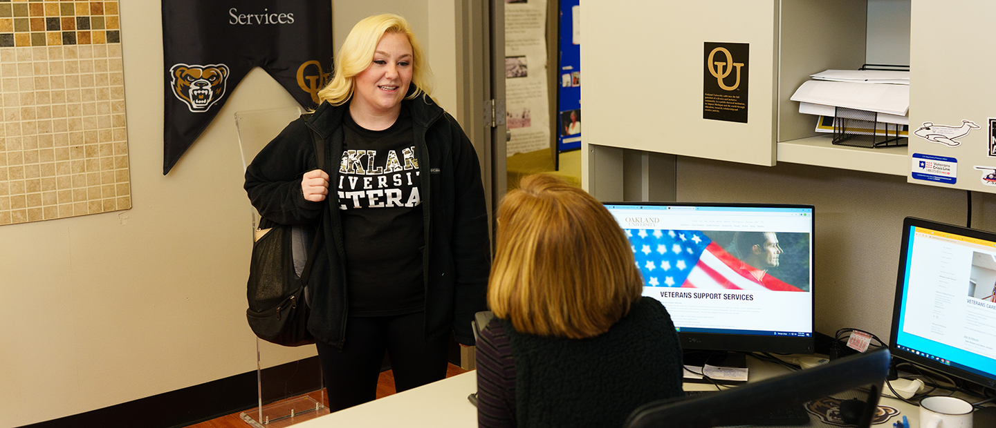 Young Woman in Oakland University Veteran speaks to a woman in the Veteran Support Services office