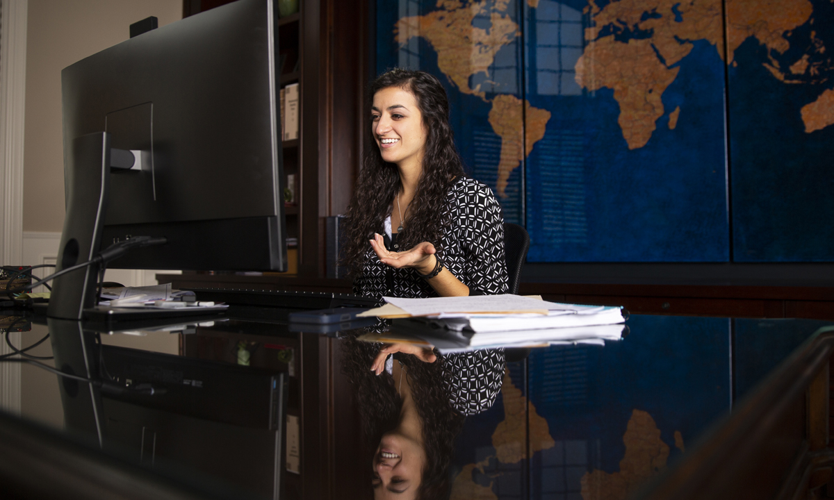 Image of a young girl sitting at a desk smiling. 