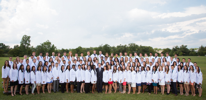 O U W B class of 2021 wearing white coats in a group photo outdoors 