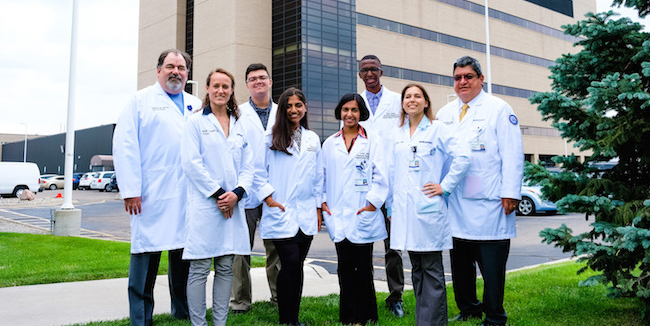 group of medical students and professionals in white lab coats posing for a photo outside