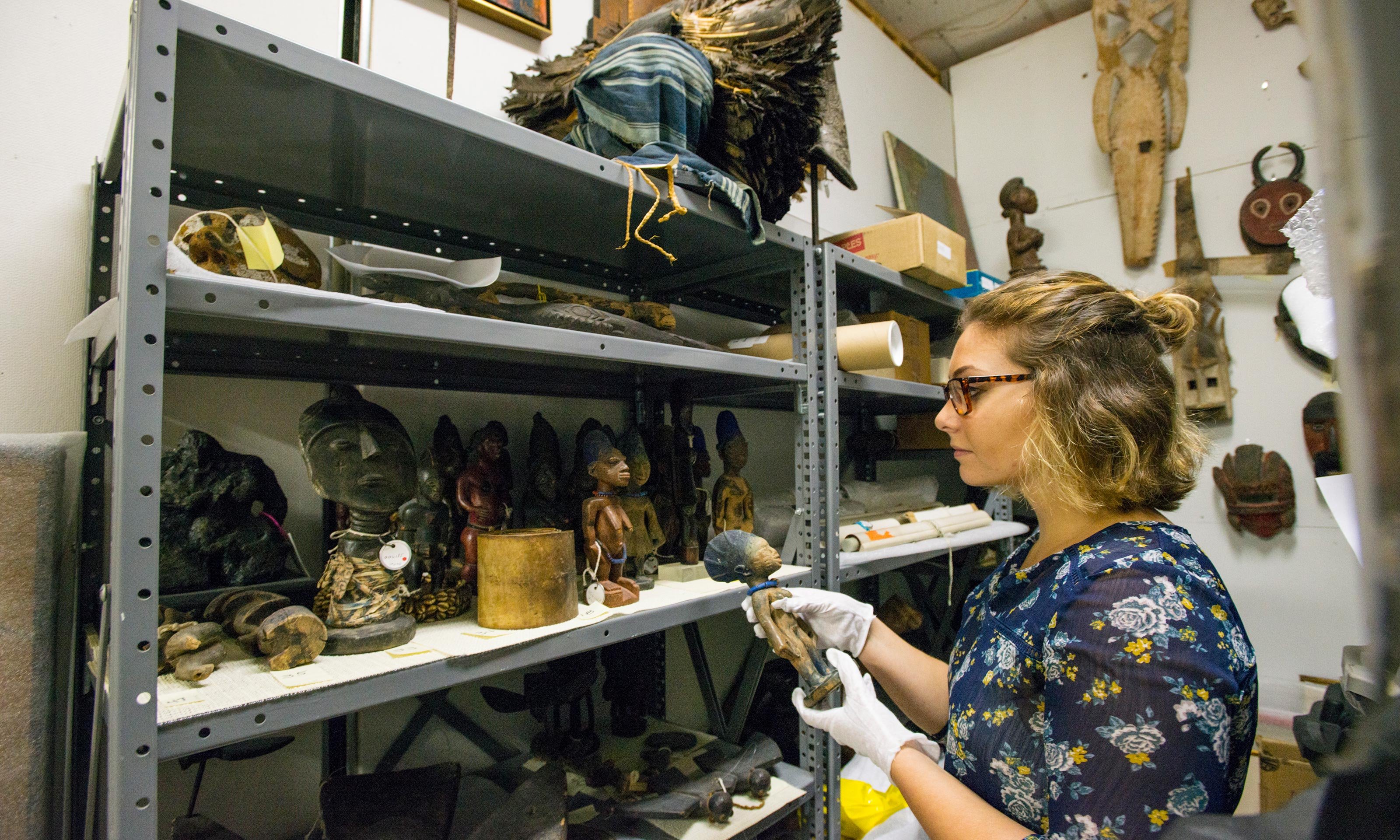 Oakland University student Sarah Lawrence handles African sculptures in the back storage space of the Oakland University Art Gallery