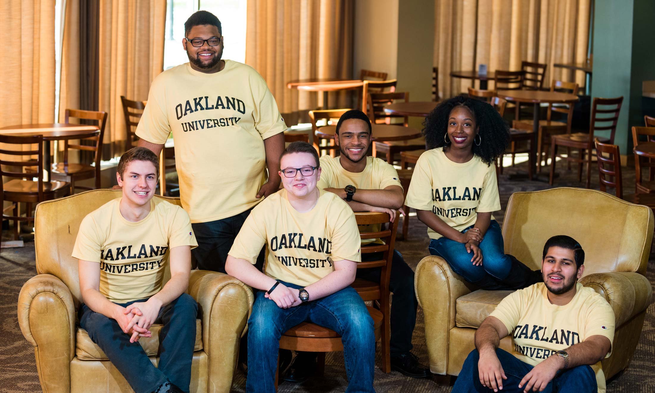 The 6 award recipients of the Oakland University 2017 Keeper of the Dream posing in a room with tables and chairs behind them