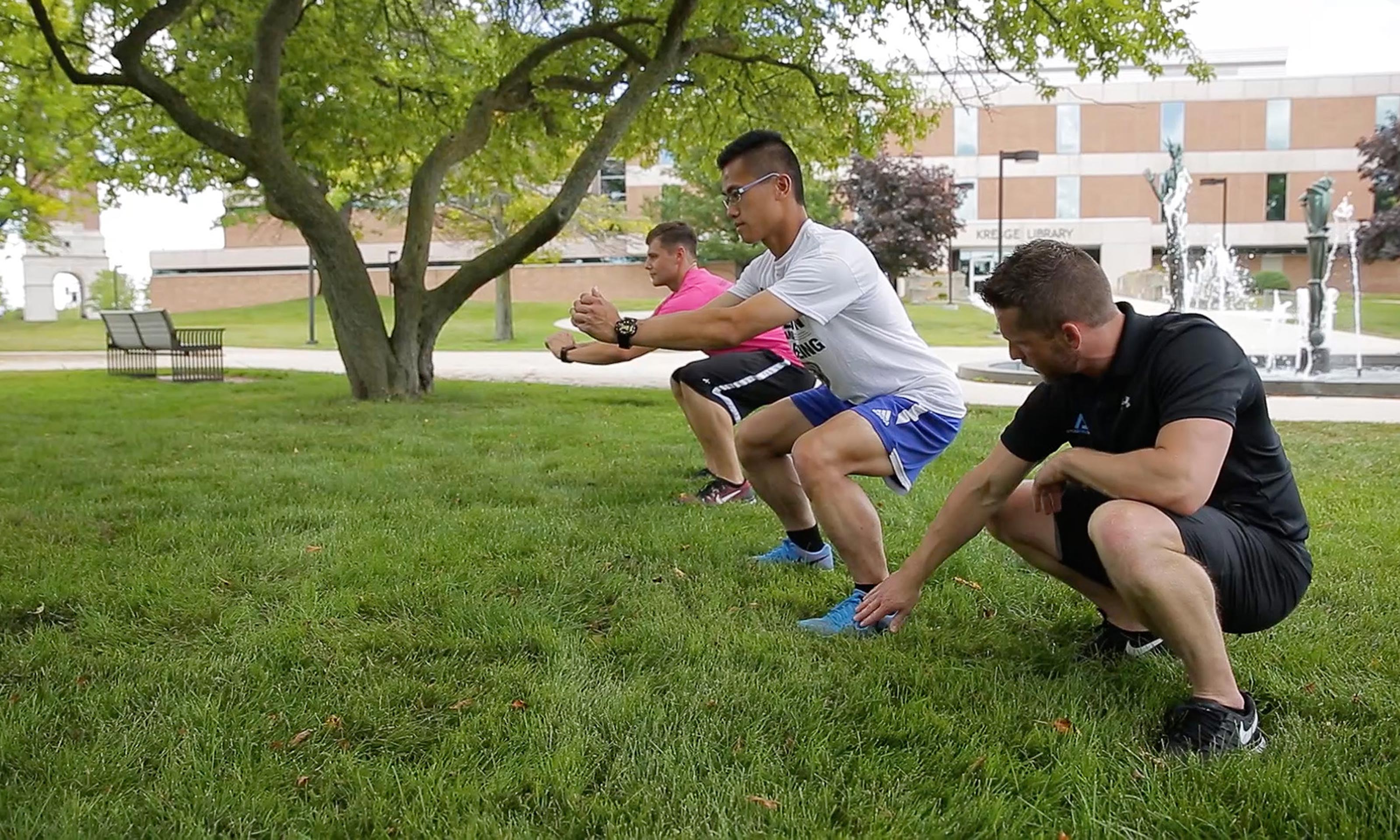 Jared Freeman  practices squats with Oakland University students