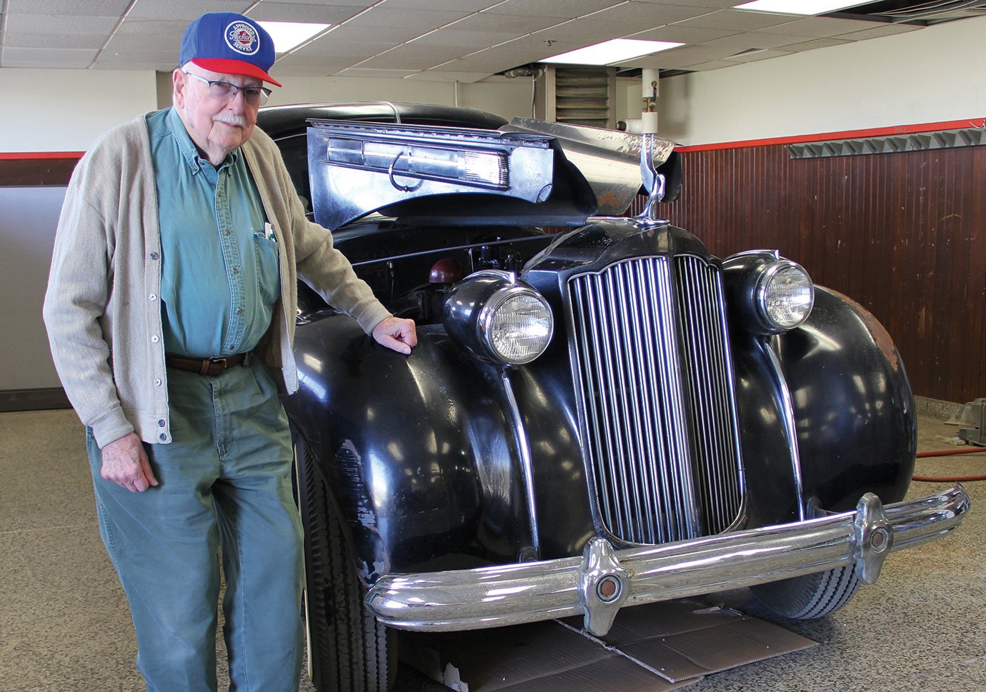 Charles Blackman stands next to a black vintage car