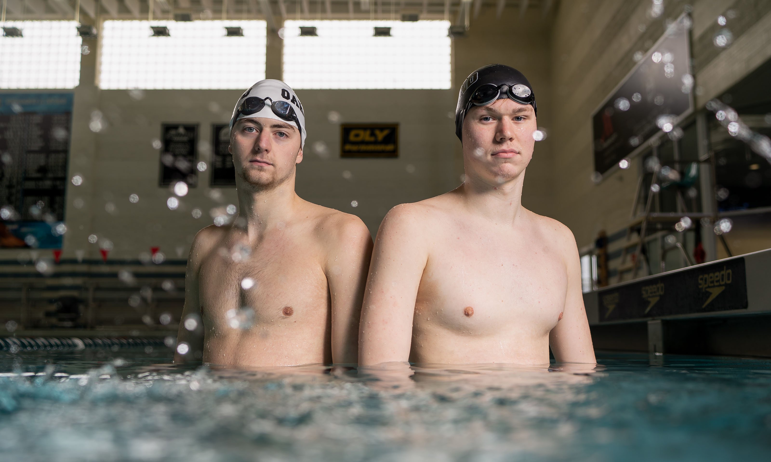 two male swimmers with caps and goggles standing in water
