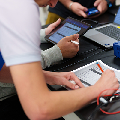 Students looking at schedules on paper and on computers.