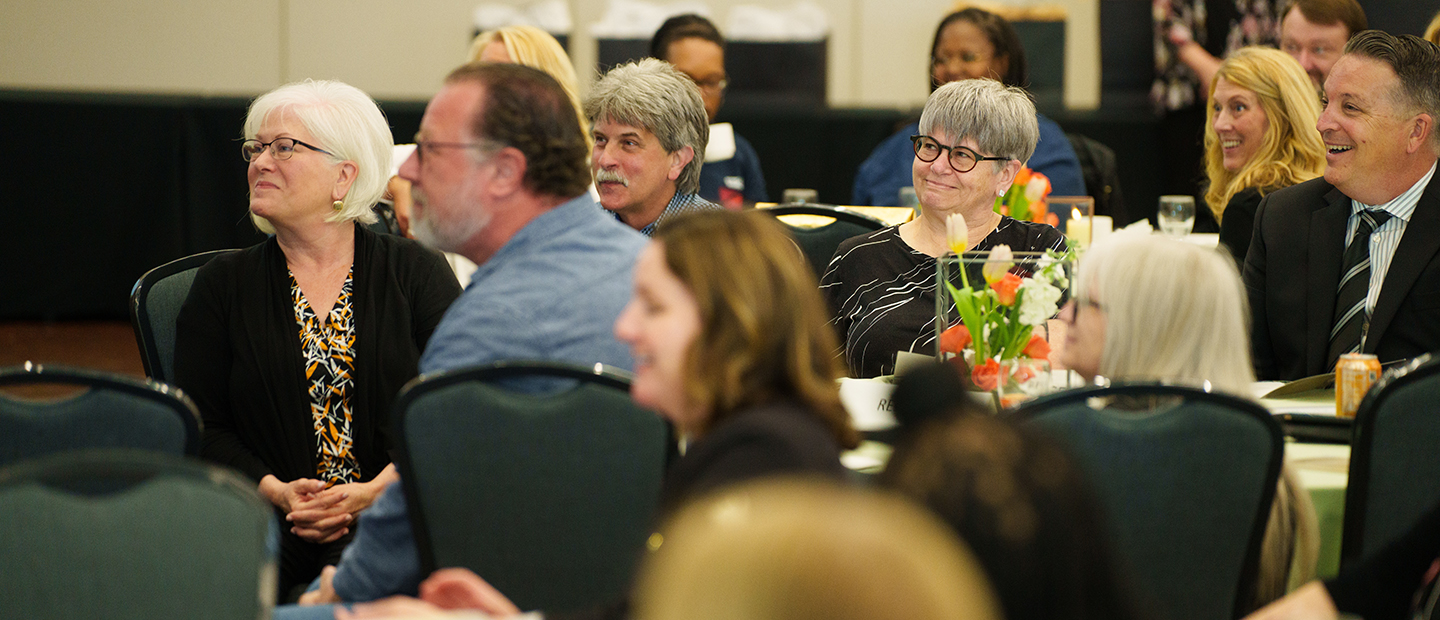 A table full of OU employees engaged with a speaker at the front of the room
