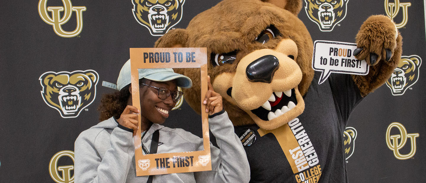 A first generation college student posing with the Grizz mascot