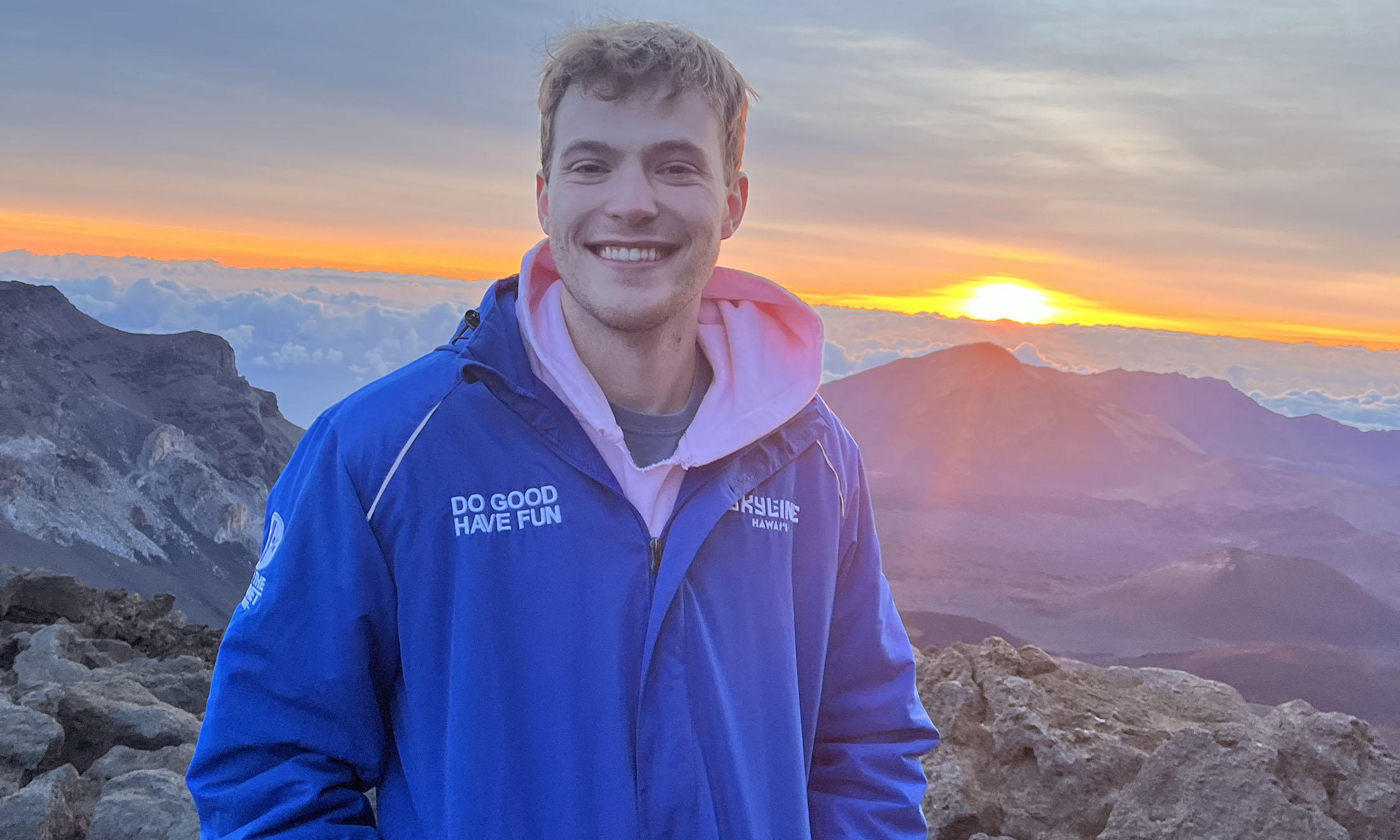 Brandon Owens poses for a picture in a front of a mountain during a sunrise.