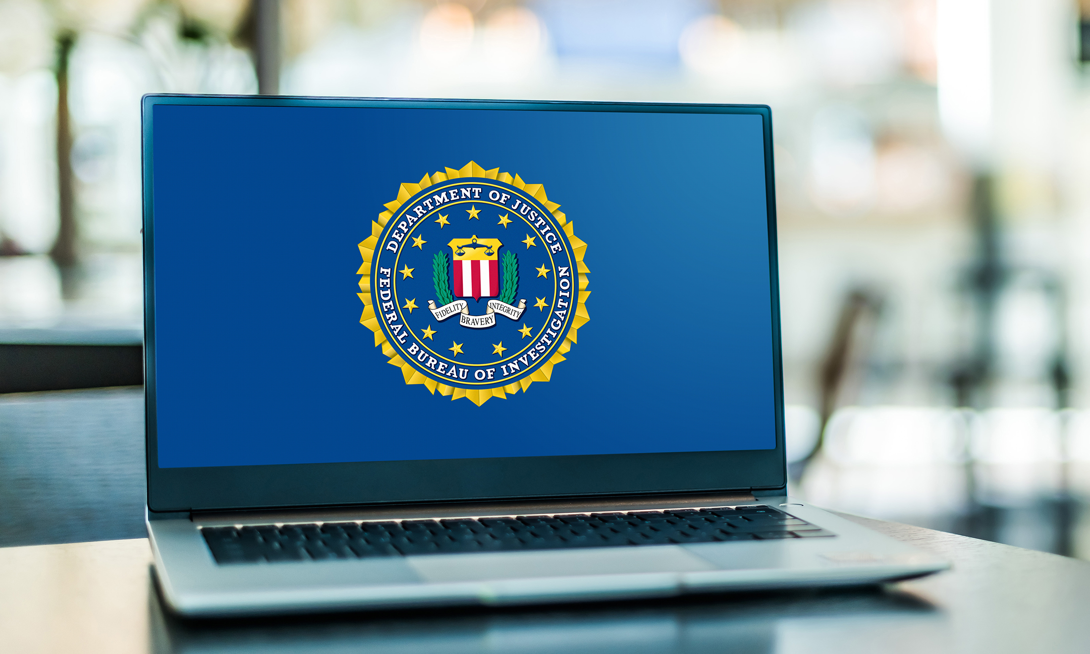 A computer sits on a desk with the FBI logo on it.