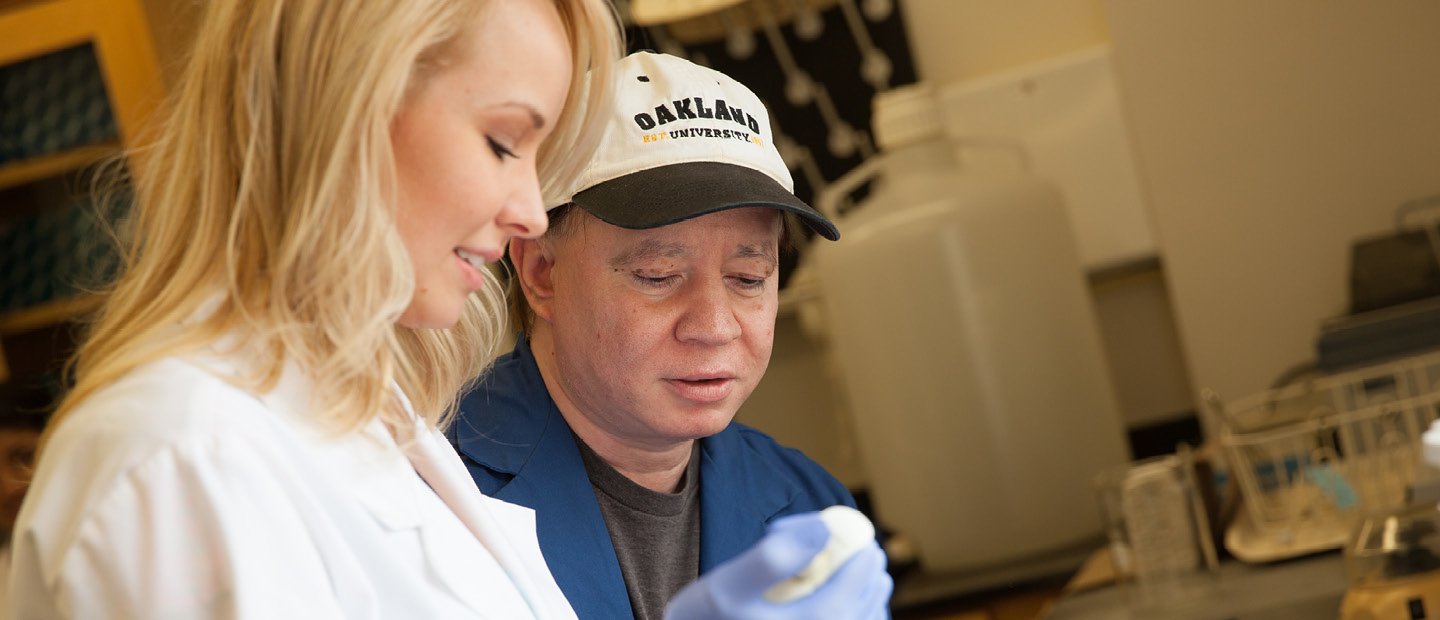 man in a hat and woman in a white coat working in a lab