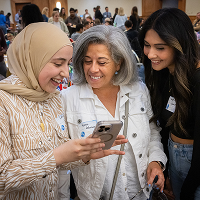 Students at an event, looking at a phone screen together