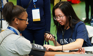 A student takes a blood pressure reading at the health fair