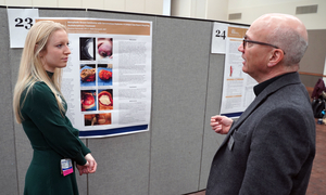 A student stands in front of her research poster