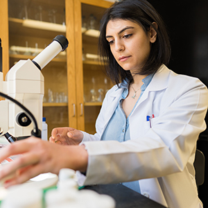 A woman in a lab coat works at a microscope