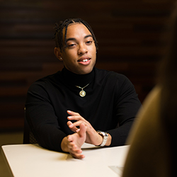 Woman sits across desk from another person.