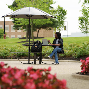 A student sitting at a table on campus.