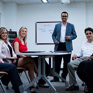 Teachers around a table looking and smiling at the camera