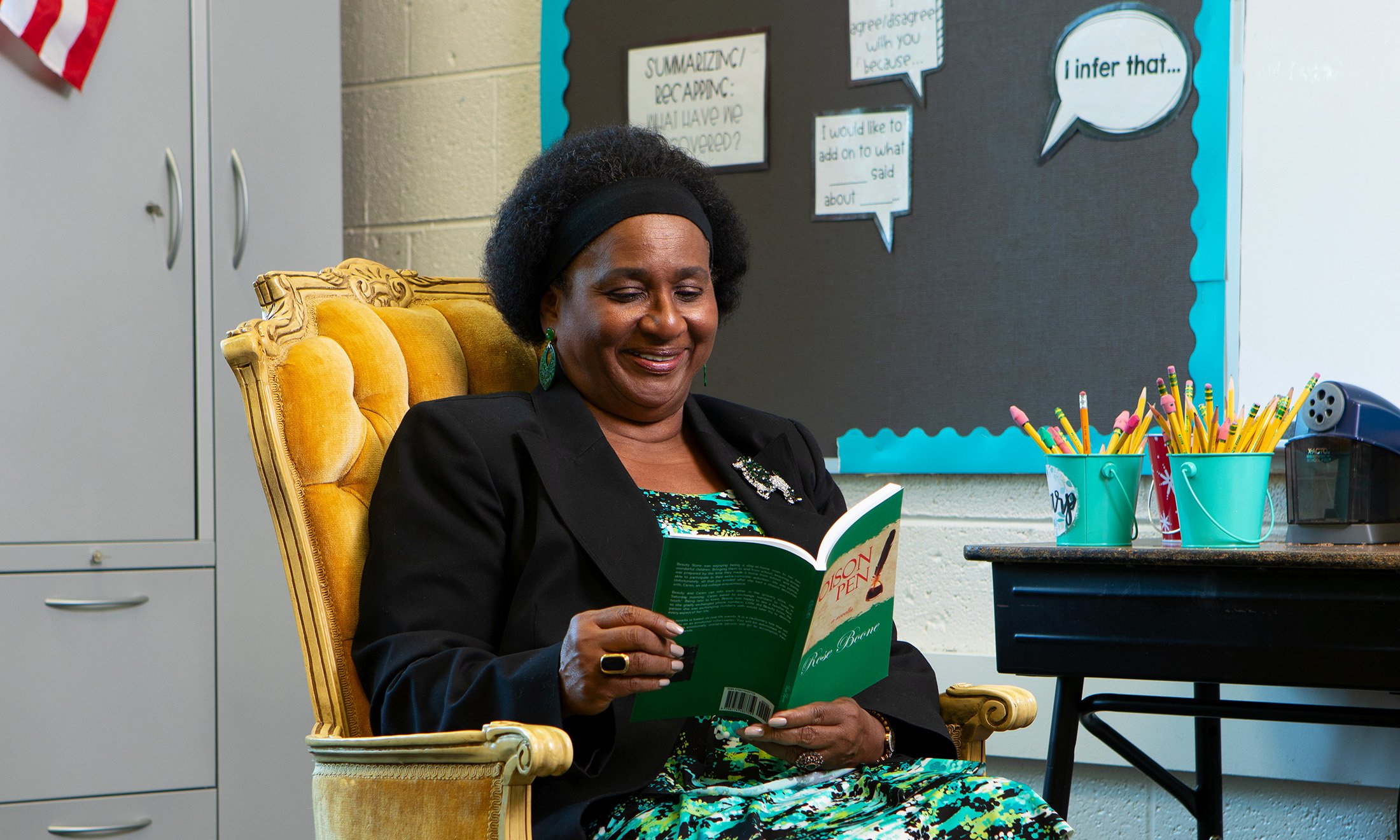 Rosaline Boone in a golden arm chair reading a book