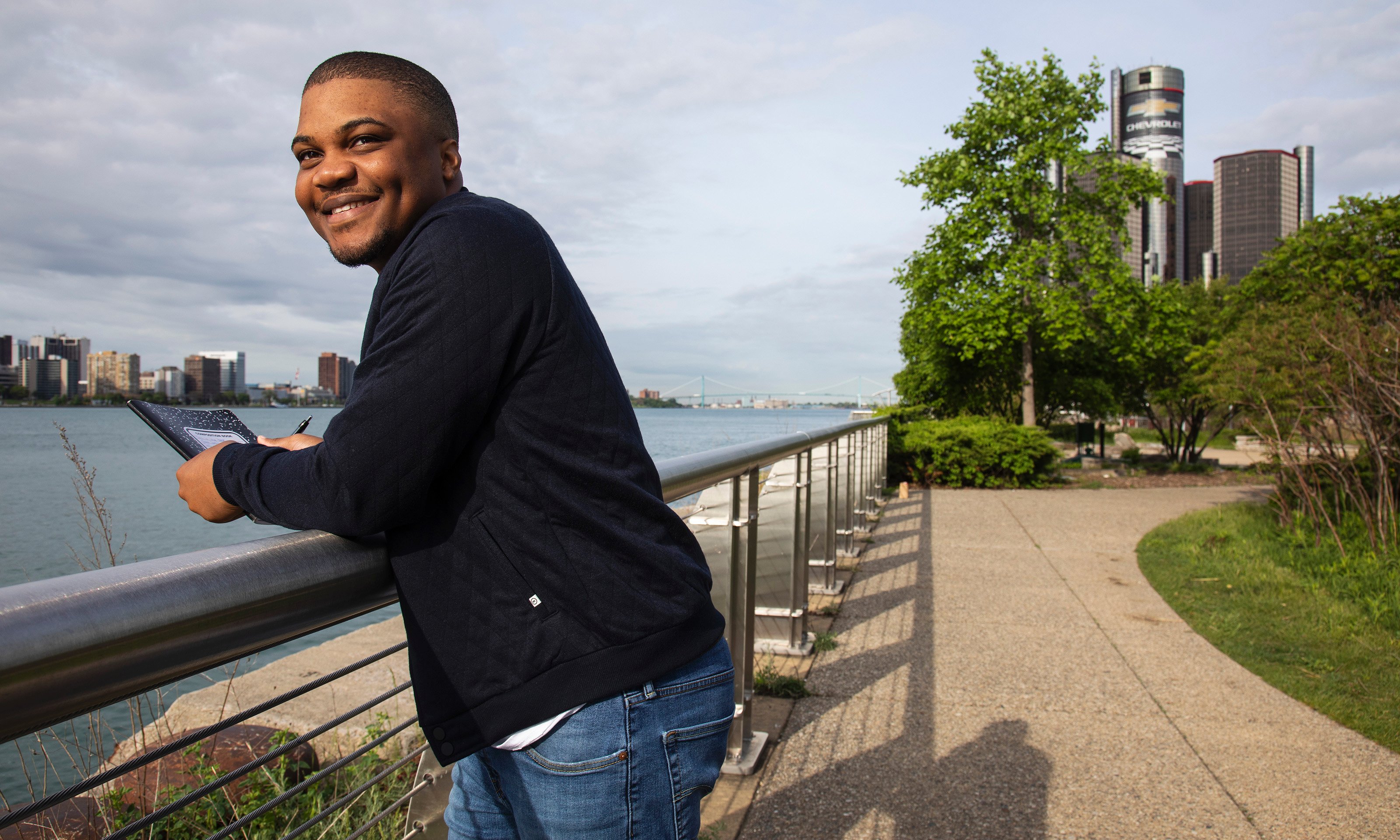 A man leaning on a bar with a notebook