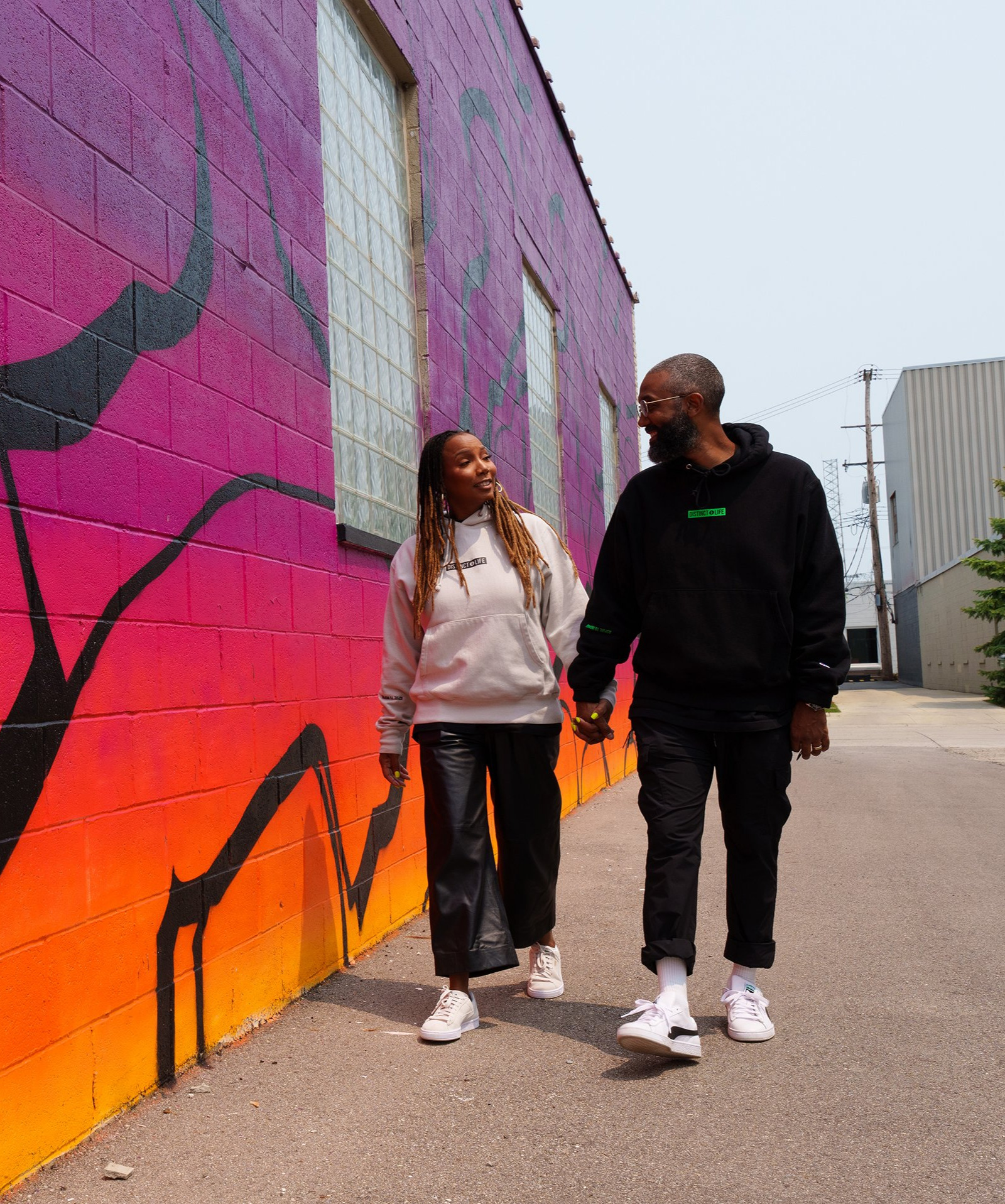 Two people walking outside next to a vibrant wall