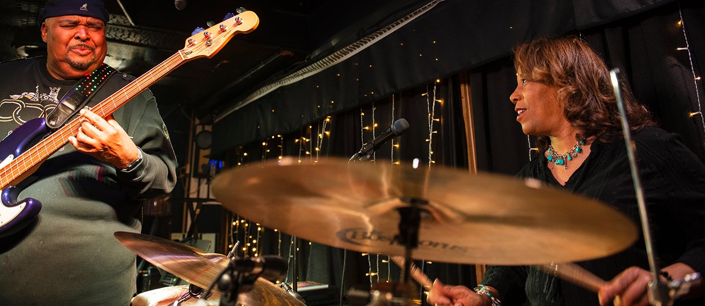 A woman playing drums and a man playing bass