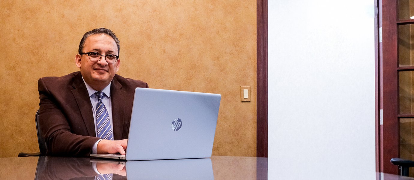 A man sitting at a table working on a laptop