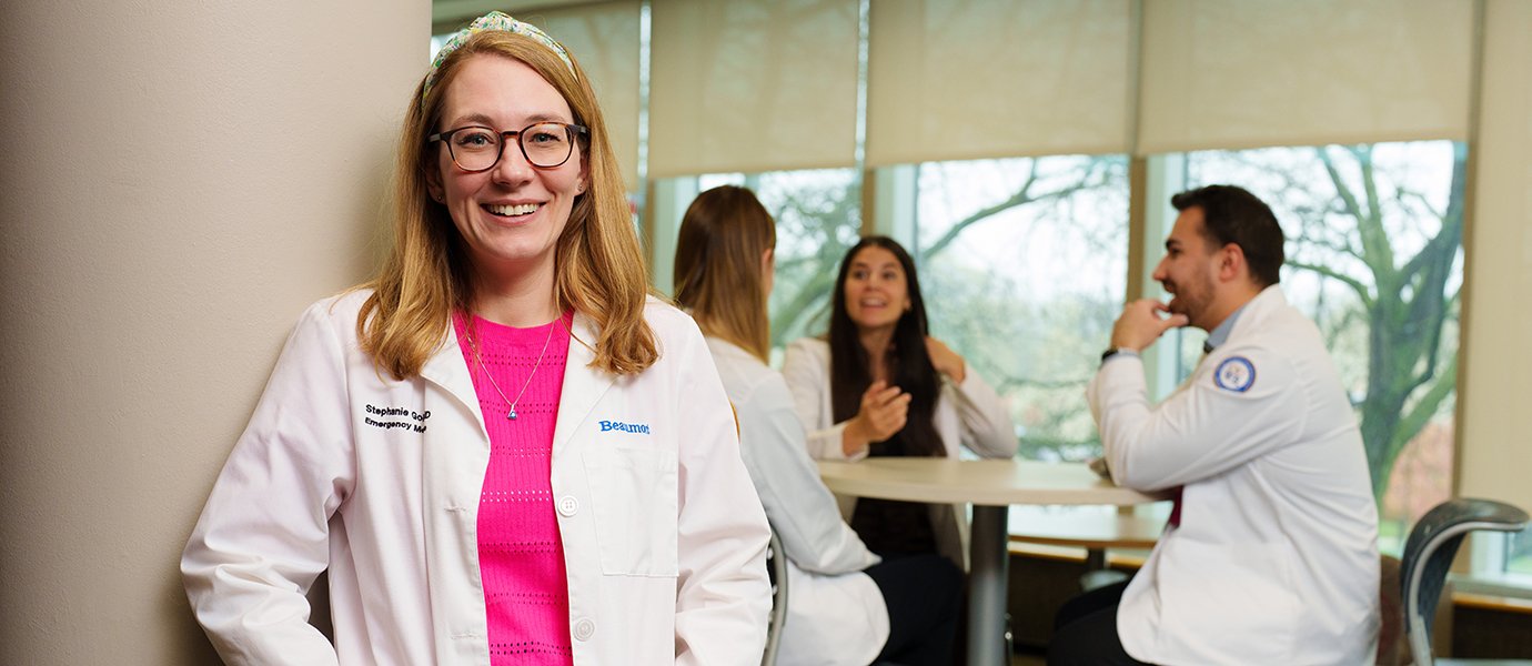 A woman smiling with people sitting at a table behind her