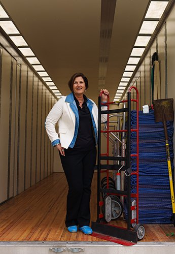 A woman in the back of a moving van holding a dolly