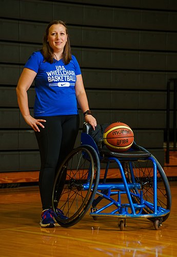 A person next to a wheelchair and basketball