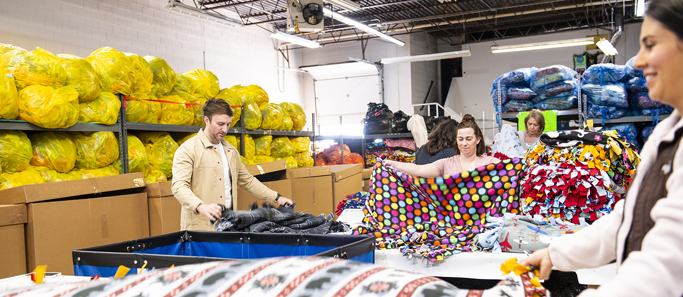 People working in a warehouse folding blankets