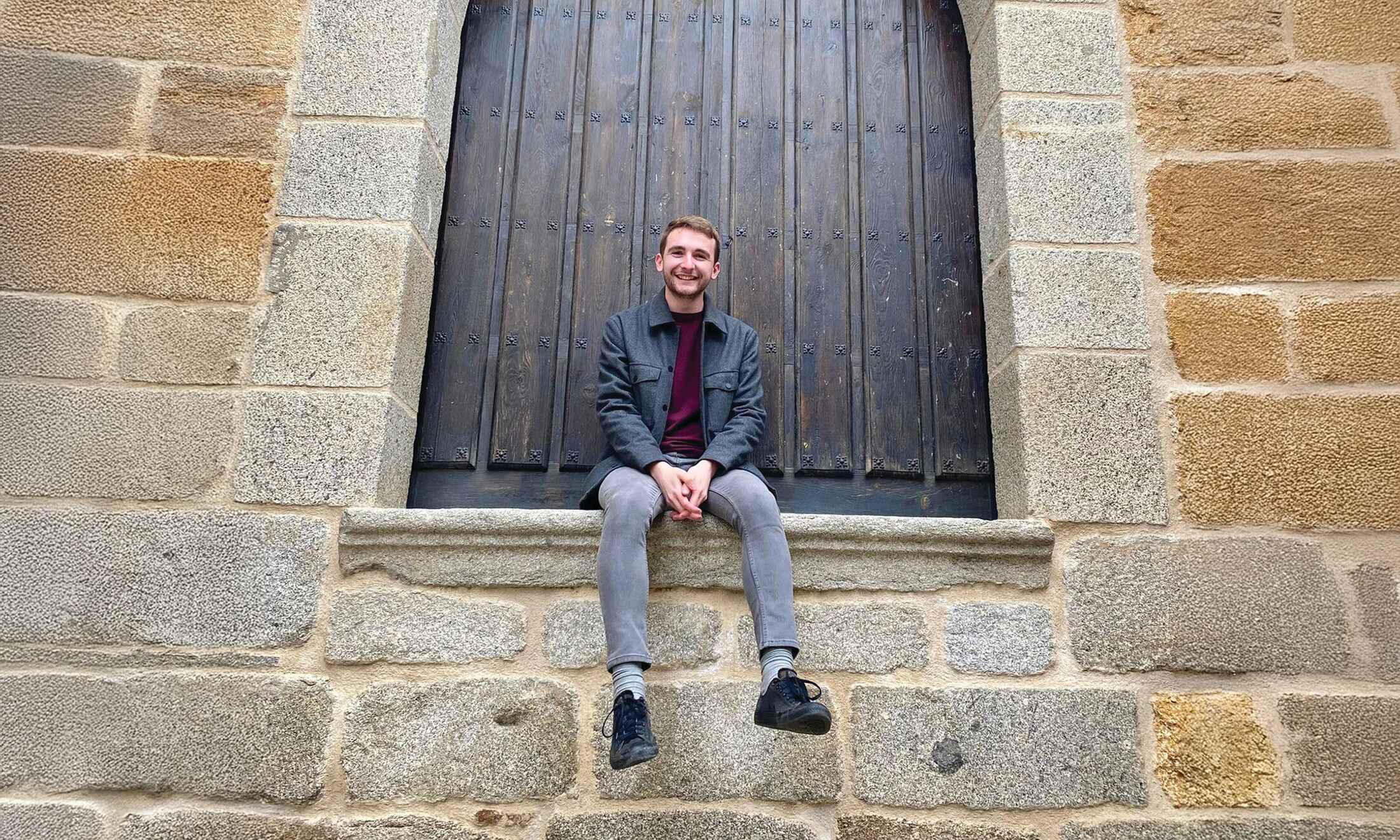 Man sitting along brick wall