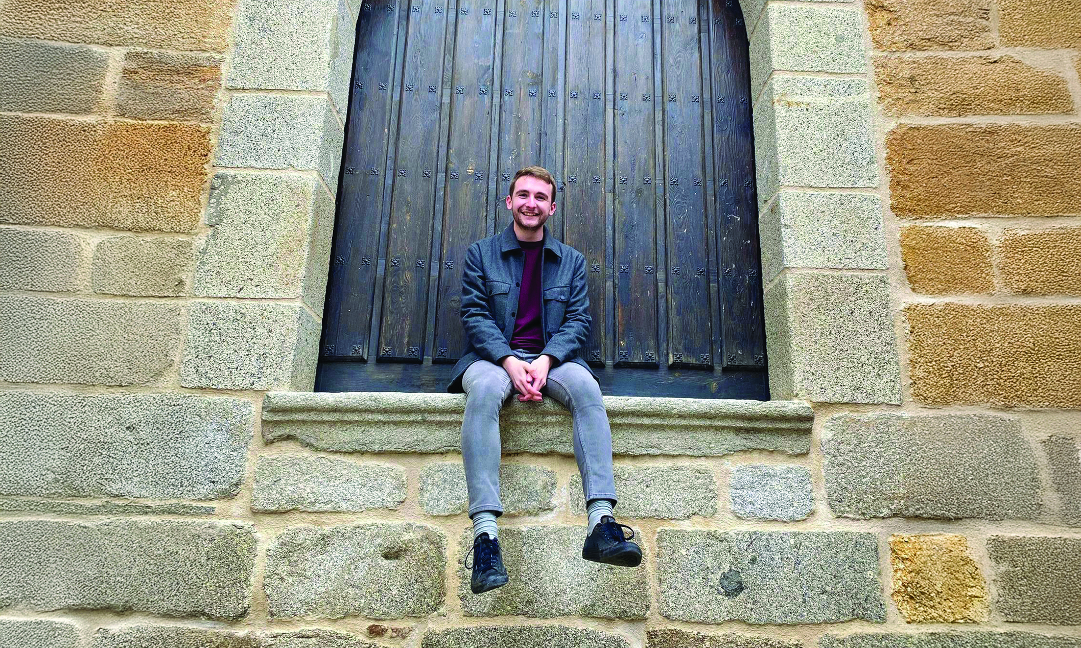 Man sitting along brick wall