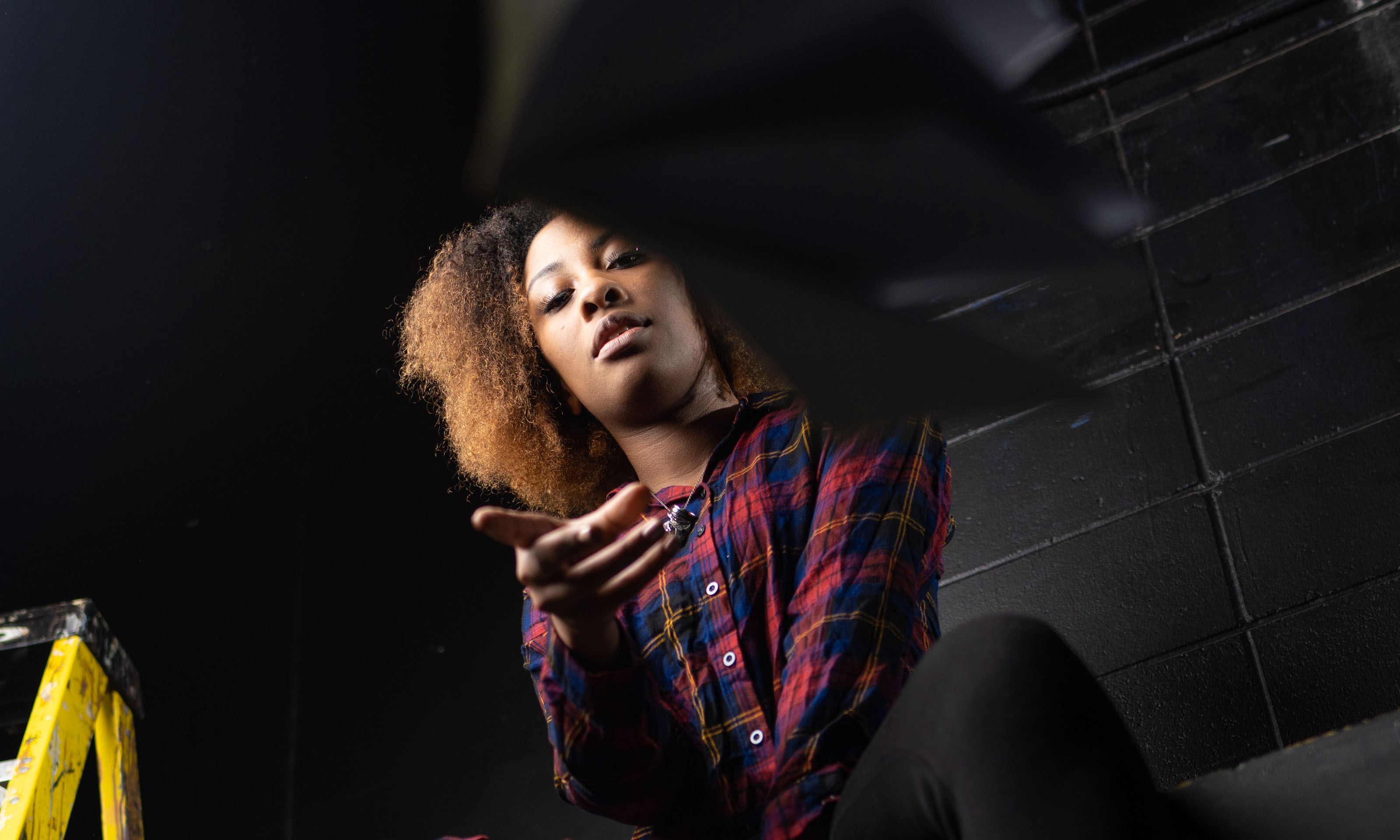 student sitting on box throwing book toward camera