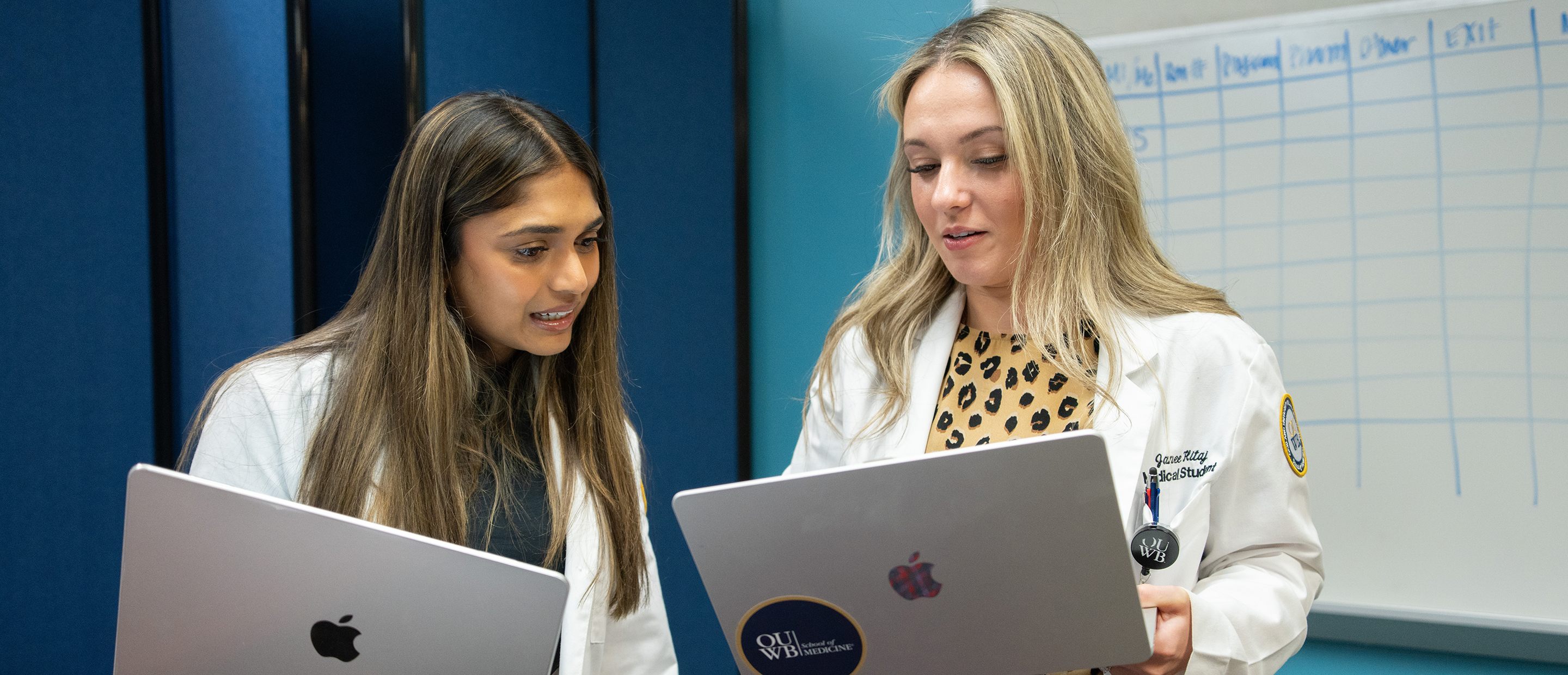An image of two students with each holding a laptop
