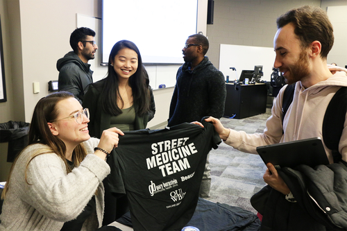 An image of a medical student handing a shirt to a classmate