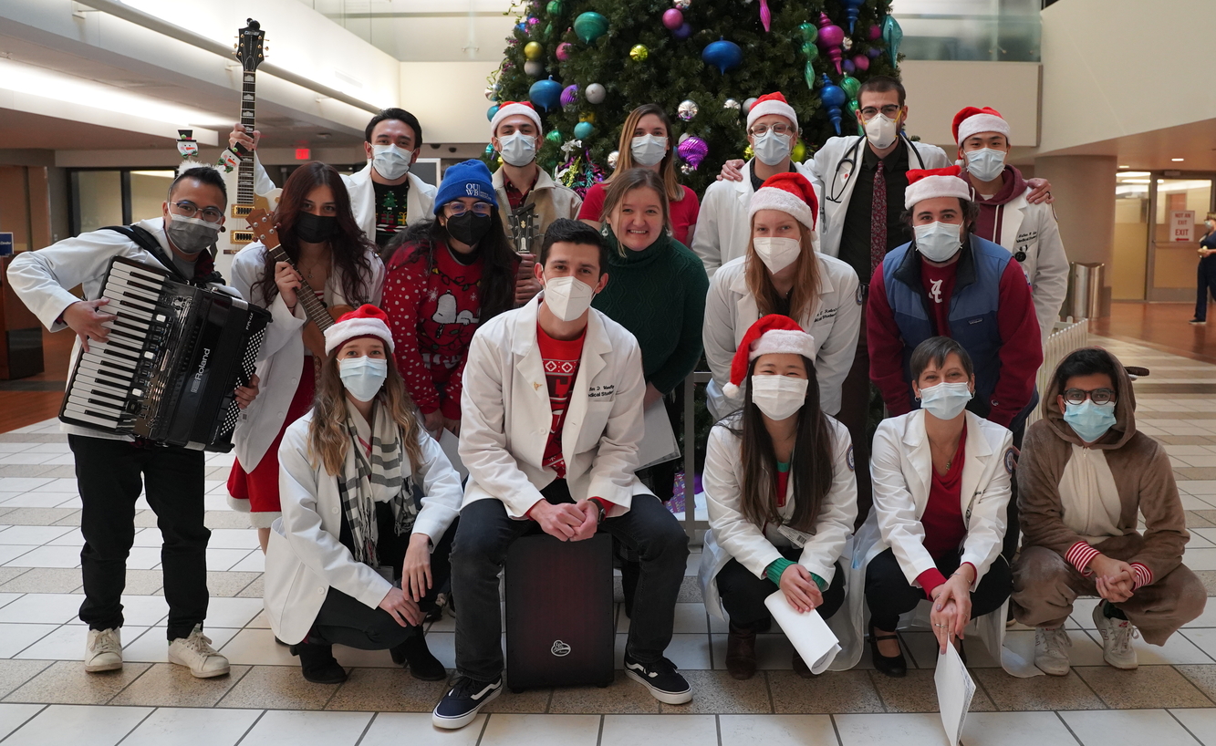 An image of holiday singers in front of a Christmas tree