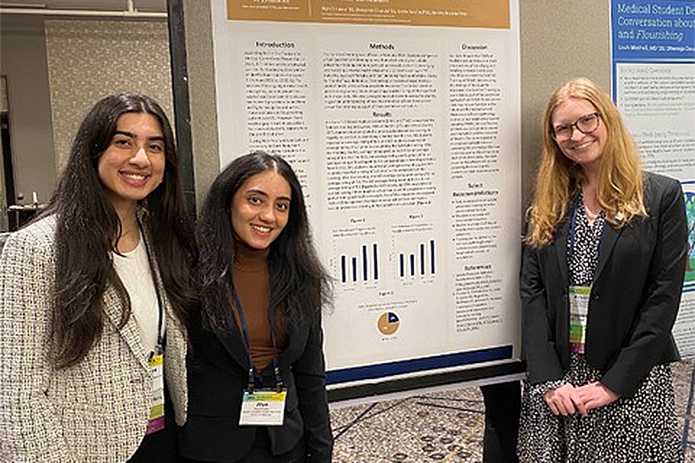 An image of three students by a poster