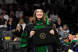 A new grad holds up her degree