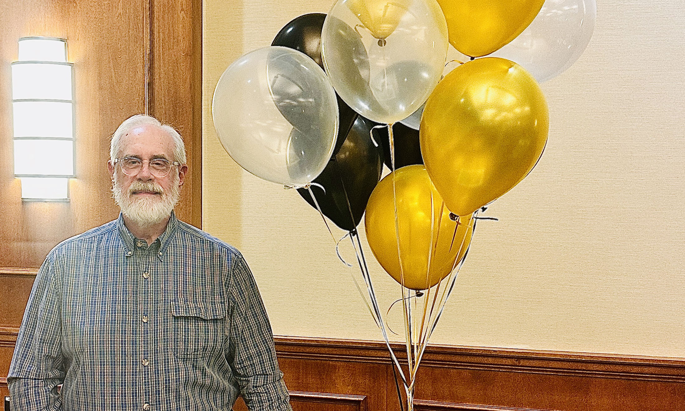 a retiring professor standing next to the balloons