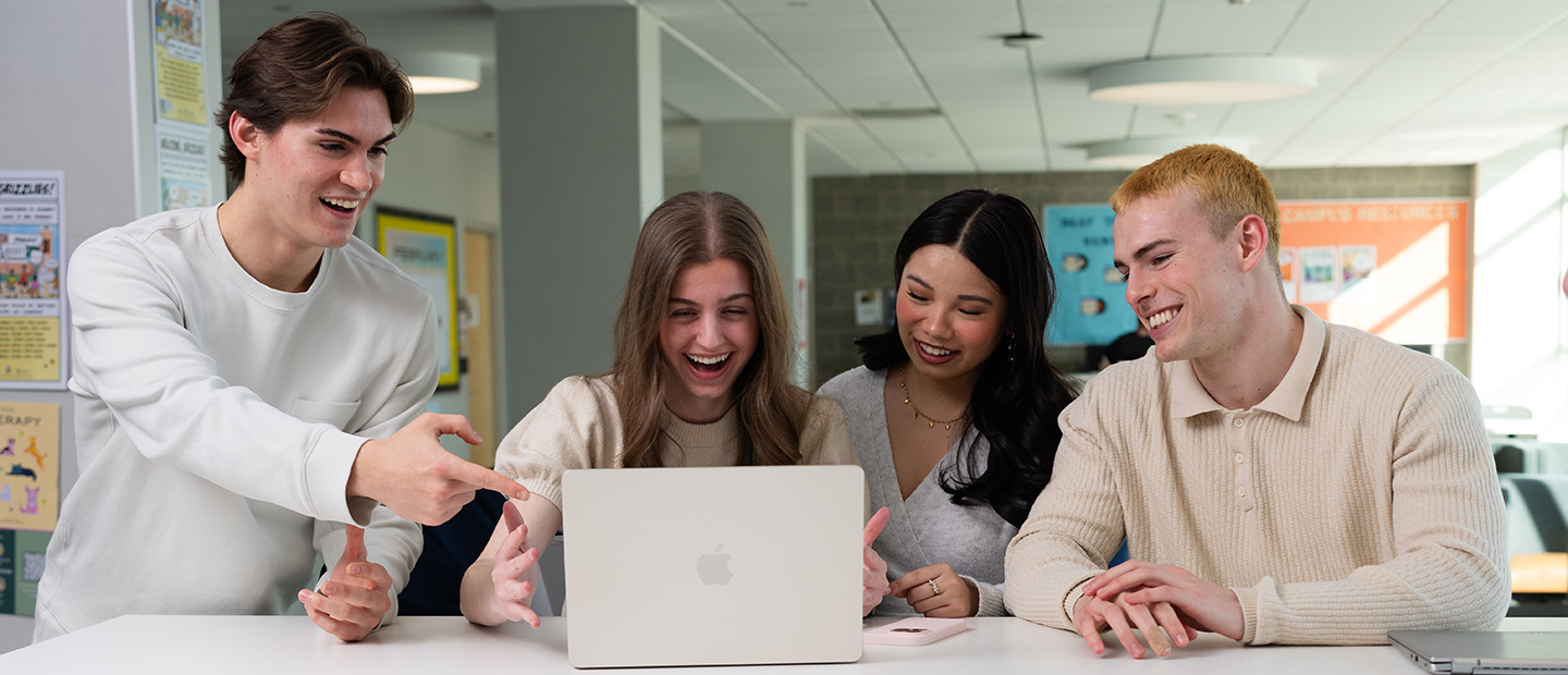 Four students looking at a laptop screen