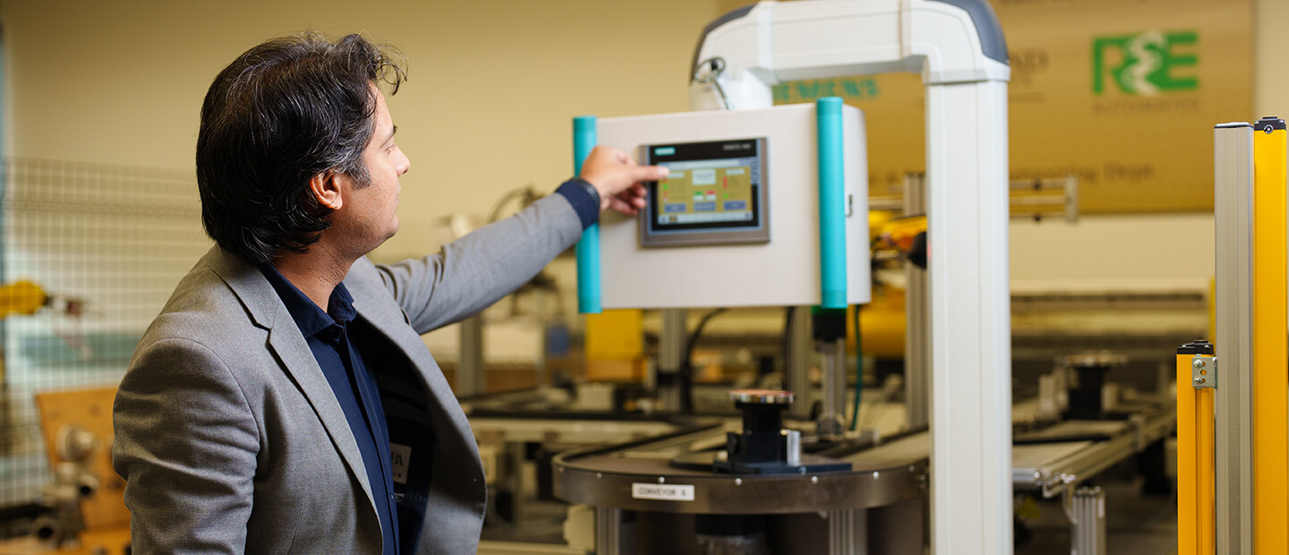 A man works on a touch screen attached to a piece of equipment