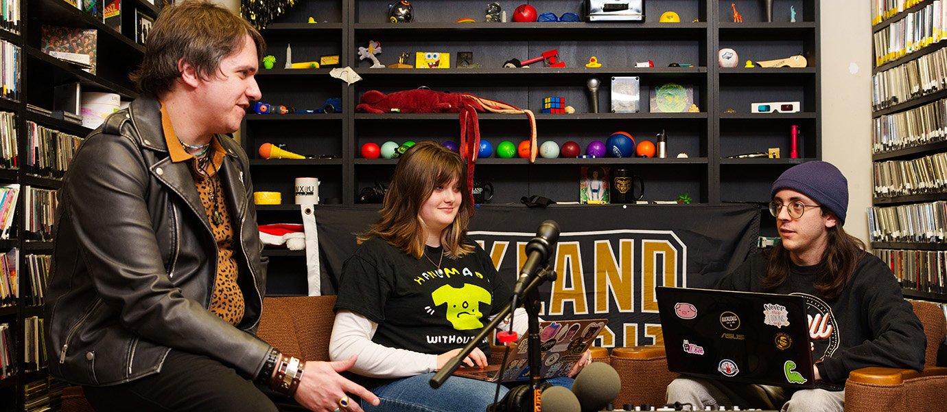 Three people sitting in a radio station